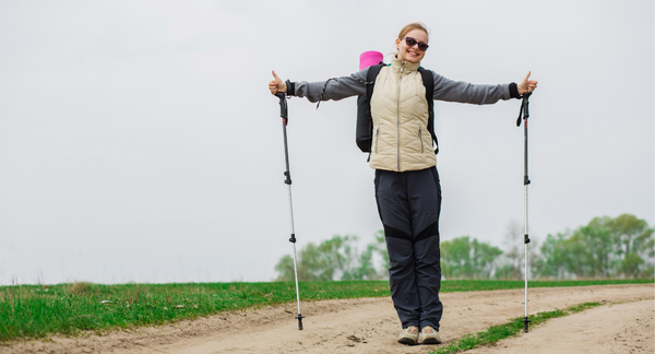 Mujer mayor de 45 años practicando marcha nórdica al aire libre, mostrando felicidad y bienestar